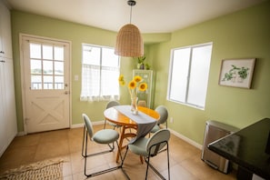 A dining area with a round table, chairs, a hanging light fixture, and a view of the outside through a window. - Cozy Home with Downtown View -- 10 min drive to downtown! (San Diego)