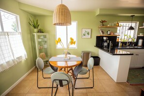 A kitchen with a dining table, chairs, a hanging light fixture, and a window with curtains. - Cozy Home with Downtown View -- 10 min drive to downtown! (San Diego)