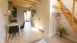 A modern interior with a dining area, kitchen, and wooden staircase.