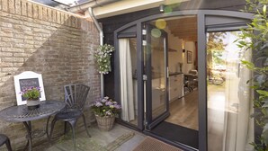 A modern outdoor seating area with a table and chairs, a welcome sign, and potted plants.
