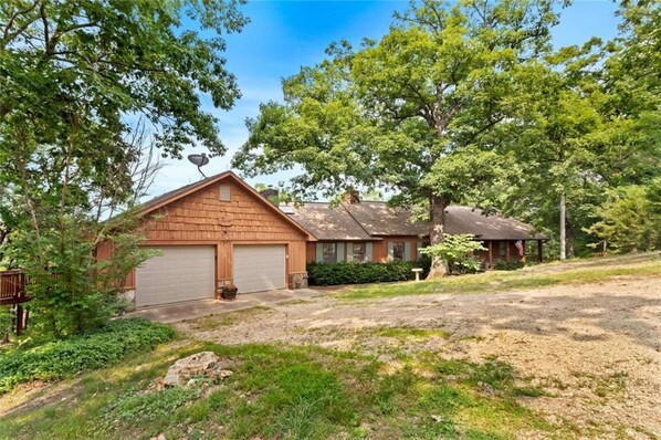 A two-story house with a garage, surrounded by trees and a grassy yard.