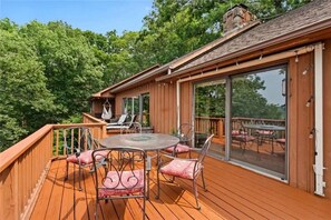 Enjoy dining or socializing on the deck with a round table and four chairs, surrounded by lush greenery.