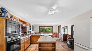 A modern kitchen with wooden cabinets, a central island, a built-in oven, a refrigerator, and a stove. - White River Mountain Manor- Million dollar view (Eureka Springs)