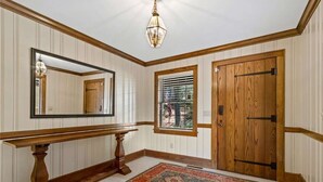 A hallway with a wooden bench, a large mirror, a window with blinds, and a door. - White River Mountain Manor- Million dollar view (Eureka Springs)