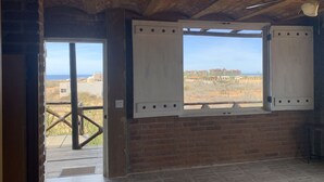 A room with a brick wall, a large window with shutters, and a ceiling fan. - Cerritos Baja Eco Pet Friendly Boutique stay (El Pescadero)