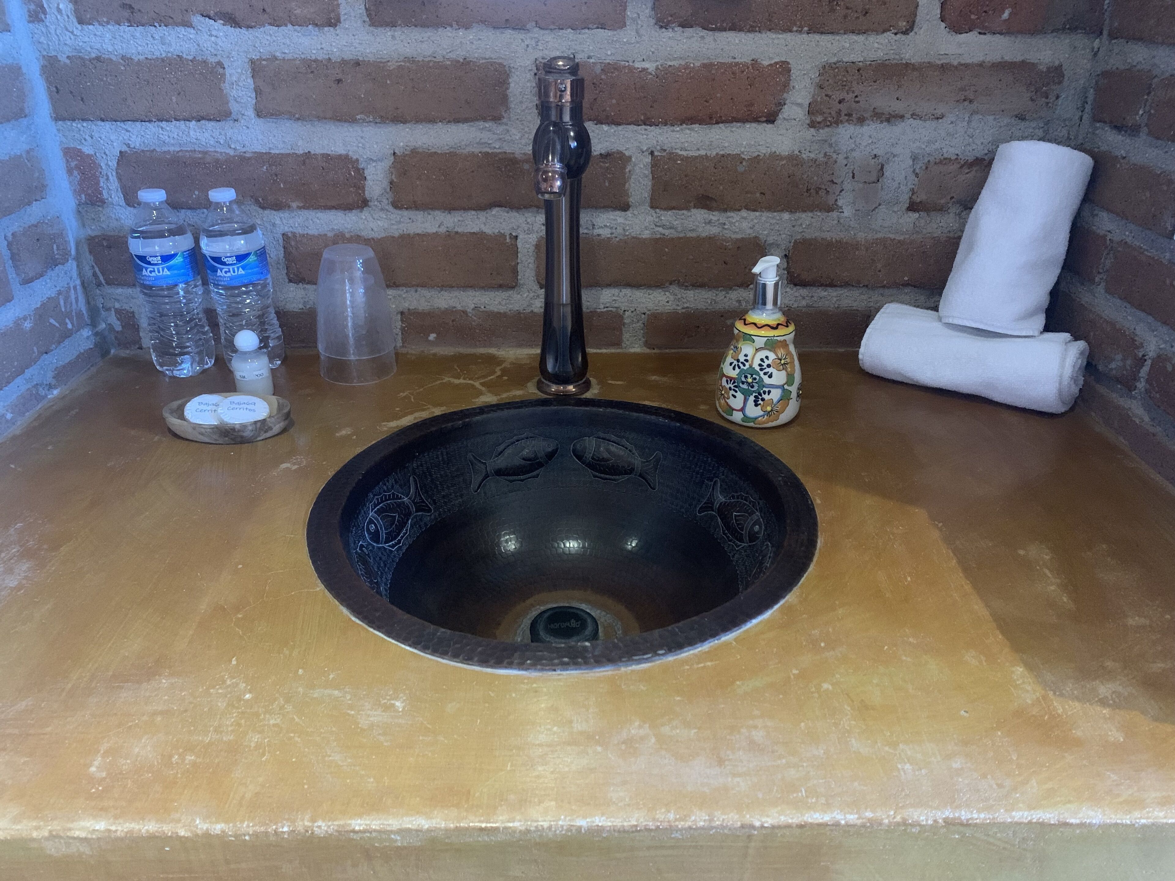 Ein Waschtisch mit schwarzer Schüssel, Armatur und dekorativer Fliesenwand.