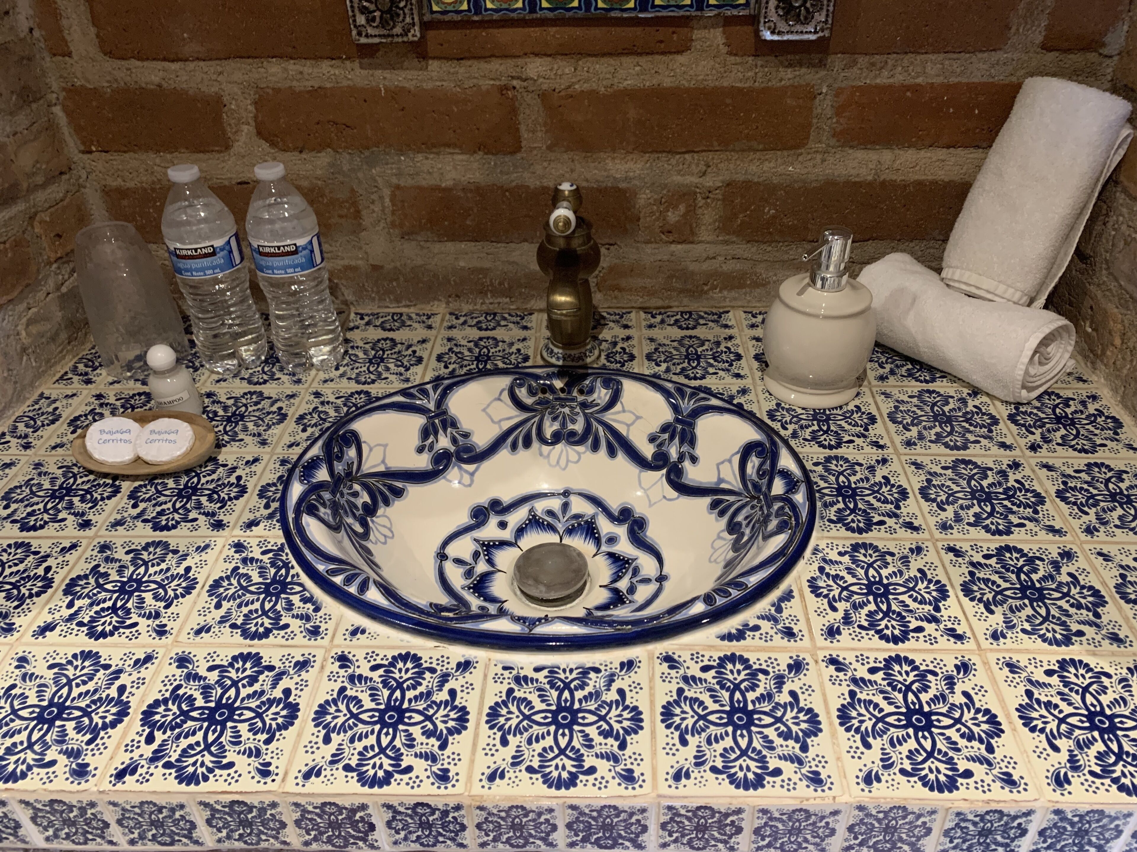 A bathroom with a blue and white tiled floor, a white sink with a blue floral design, and a towel rack.