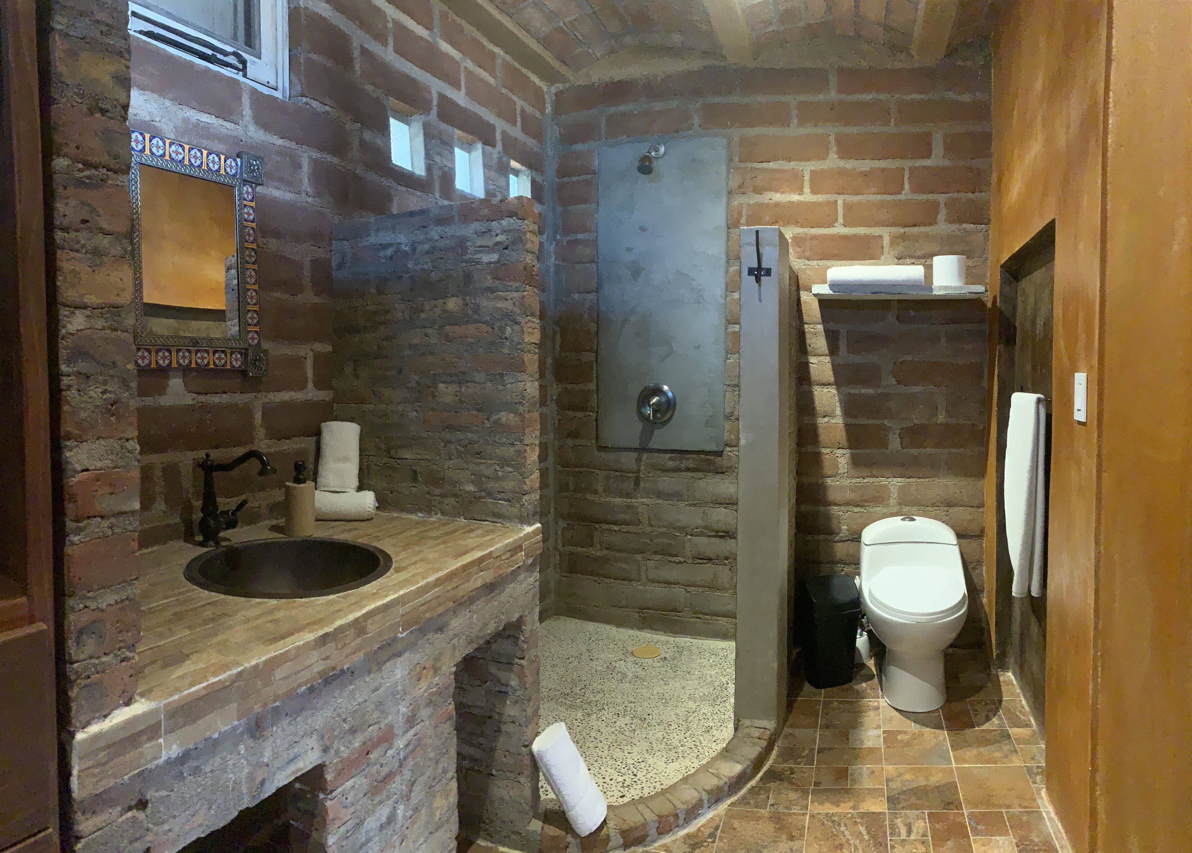 A bathroom with a stone sink, a toilet, and a shower area.
