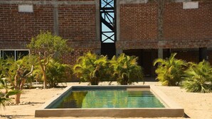 A swimming pool with a brick building in the background. - Cerritos Baja Eco Pet Friendly Boutique stay (El Pescadero)