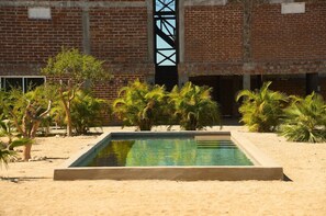 A swimming pool with a brick building in the background. - Cerritos Baja Eco friendly Boutique stay (El Pescadero)