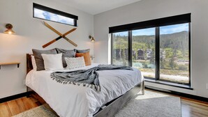 A modern bedroom with a large bed, a view of a forest, and a ceiling fan. - Downtown WP Loft 49 I Rooftop Hot Tub & Lounge I Great Views I Bunk Room I Discounted Attractions (Winter Park)