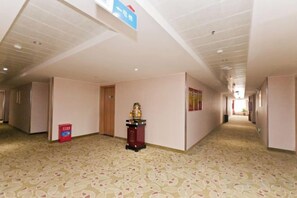 Un pasillo de hotel con alfombra estampada, una puerta de madera y un pequeño santuario.