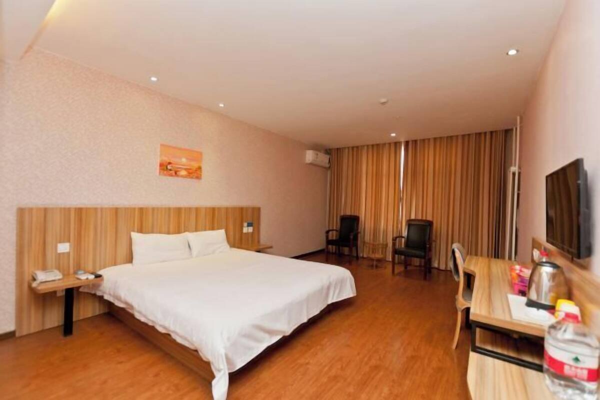 Une chambre d’hôtel comprenant un lit, une table de chevet, une chaise, un bureau et un téléviseur.
