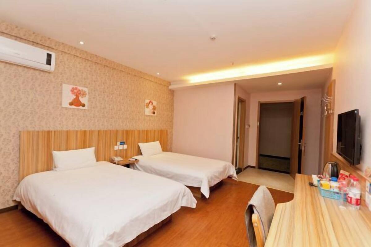 Une chambre d’hôtel avec deux lits, un bureau, une télévision et un appareil de climatisation.