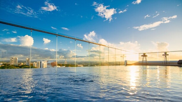 Una piscina infinita con vistas despejadas al horizonte de la ciudad y un puente al fondo.