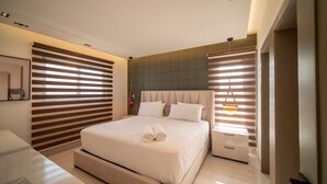 Un dormitorio moderno con una cama grande, una mesita de noche y una pequeña mesa auxiliar.