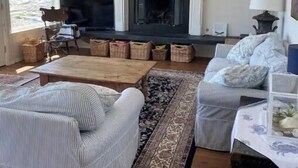 Uma sala de estar acolhedora com lareira, móveis listrados e um tapete grande.