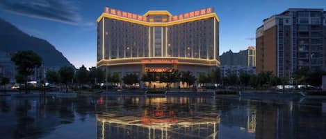 A multi-story hotel with a reflective pool in front, surrounded by other buildings.