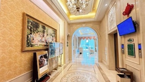 A hotel lobby with a chandelier, framed artwork, a television, and a patterned floor. - Vienna Hotel (Luofu Mountain Scenic Area High-Speed Rail Station Branch) (Boluo)