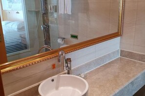 Une salle de bain avec un grand miroir, un lavabo et une douche.