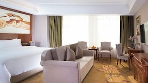 A hotel room with a large bed, a sofa, two armchairs, a small table, and a TV. - Vienna Hotel (Luofu Mountain Scenic Area High-Speed Rail Station Branch) (Boluo)