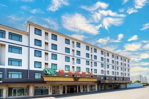 Um hotel de vários andares com fachada moderna, grandes janelas e sinalização chamativa.