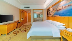 A hotel room with a large bed, a TV, a wooden dresser, and a painting on the wall. - Vienna Hotel (Luofu Mountain Scenic Area High-Speed Rail Station Branch) (Boluo)