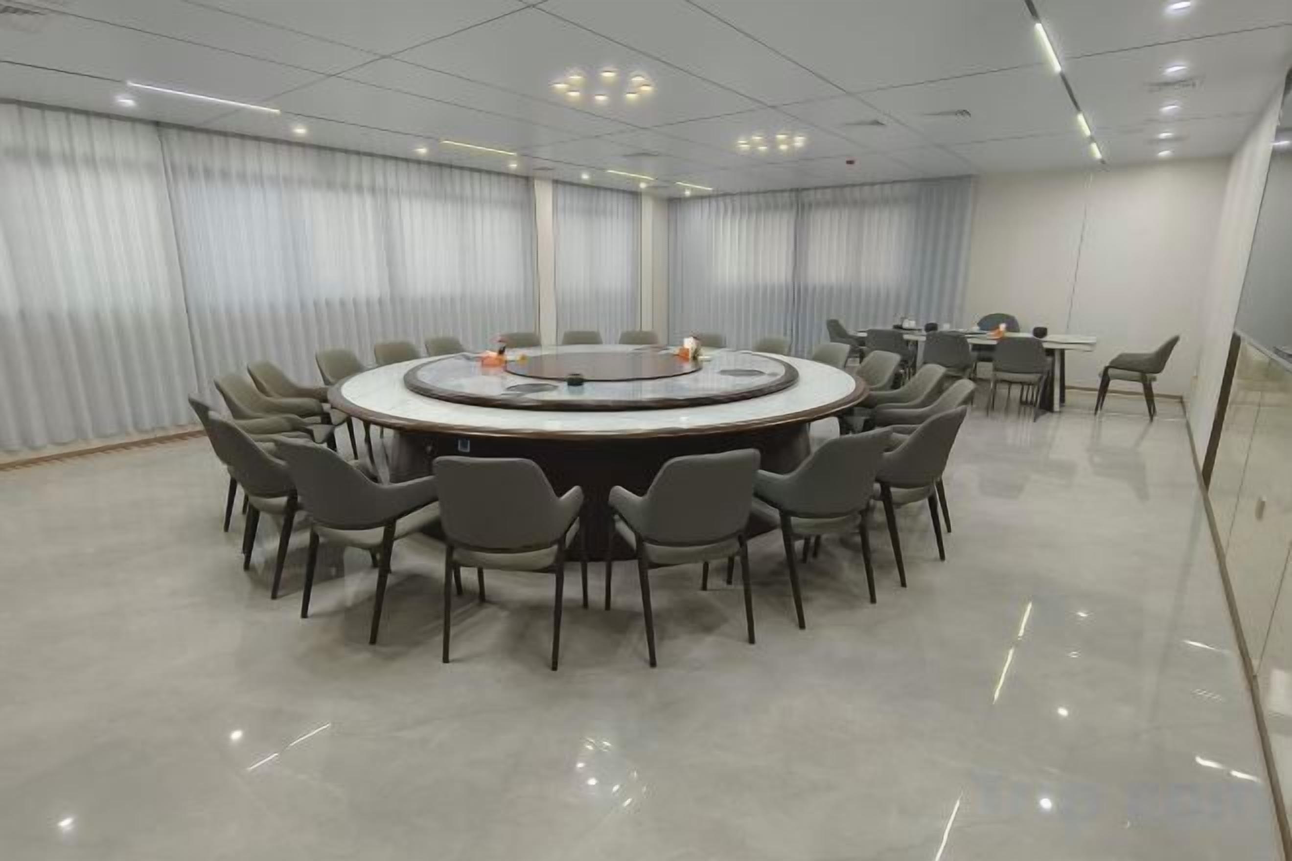 A conference room with a round table surrounded by chairs, a whiteboard, and a projector.