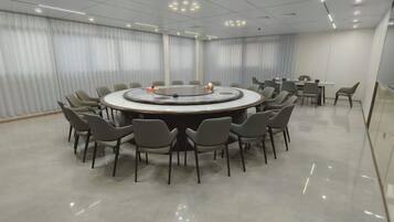 A conference room with a round table surrounded by chairs, a whiteboard, and a projector.