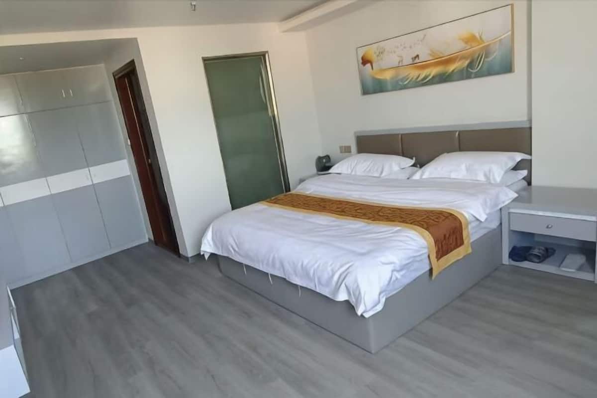 A modern hotel room with a bed, a wardrobe, a nightstand, and a painting on the wall.