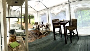A tented room with a dining area, a sink, and a green wall with kitchen utensils. - Glamping on a Safari (Wendover)