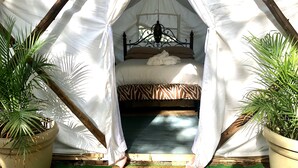 A tented room with a bed, a window, and potted plants. - Glamping on a Safari (Wendover)
