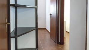 Ein Flur mit Holztür, Glastrennwand und Fliesenboden.
