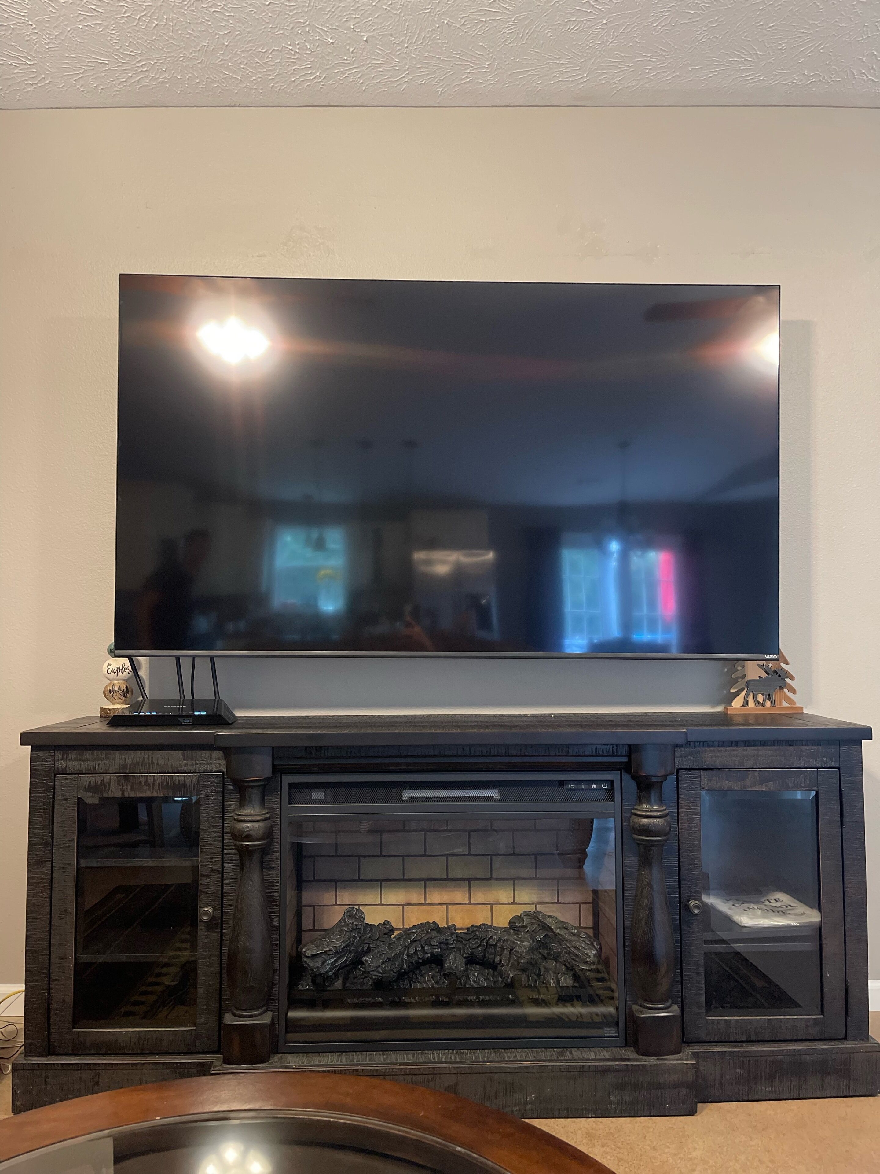 Televisão de tela plana montada acima de uma lareira com fachada de pedra.