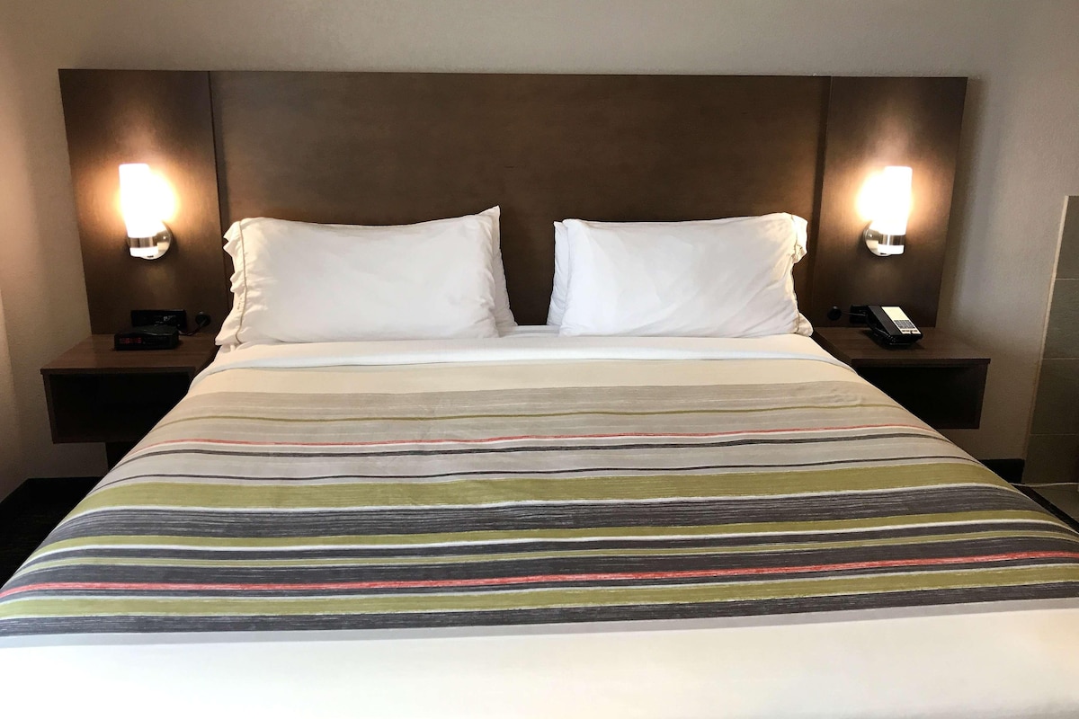 Une chambre d’hôtel avec un grand lit, deux tables de chevet et des lampes fixées au mur.