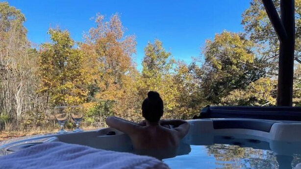Een jacuzzi met een persoon die ontspant, omringd door herfstbladeren.