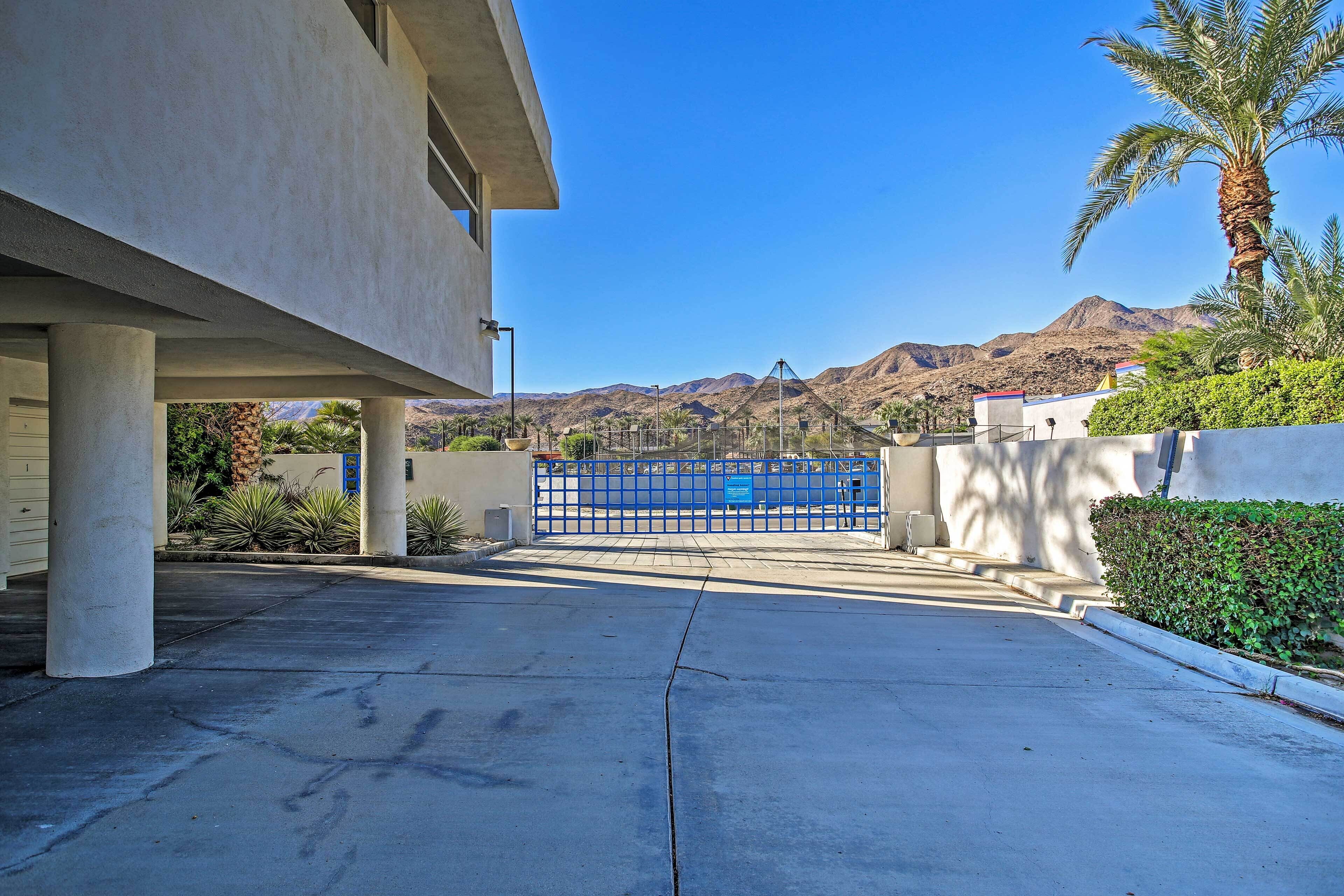 A parking area with a blue gate, concrete pillars, and a mountain backdrop.