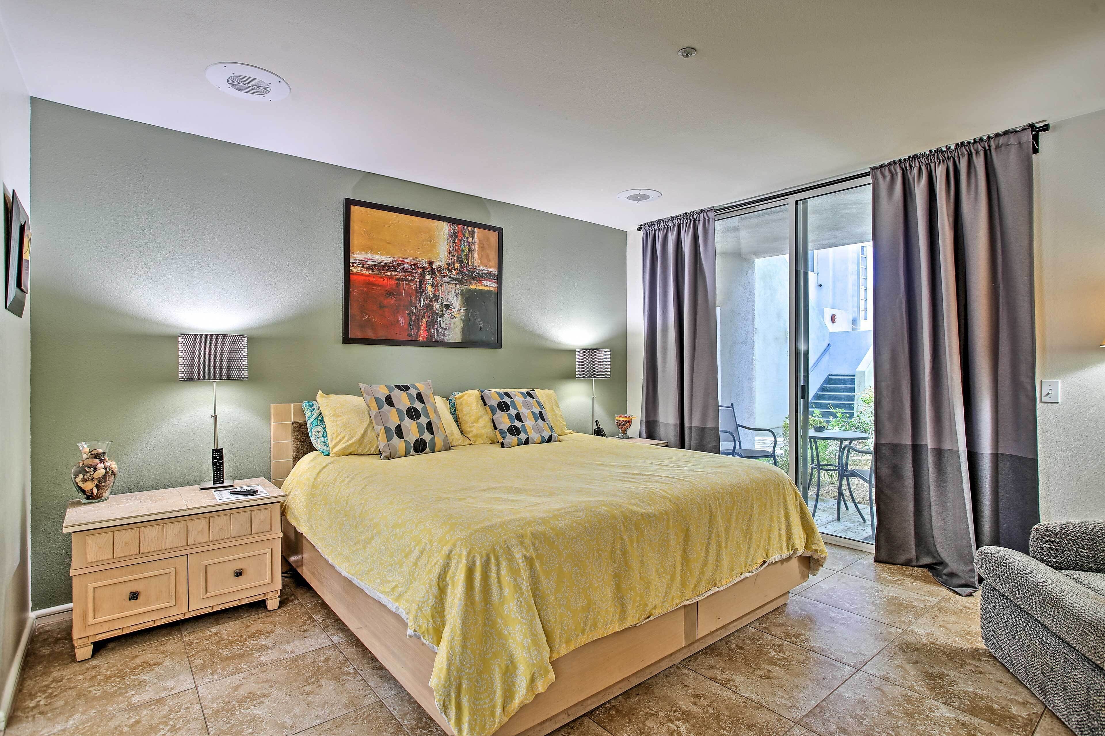 A bedroom with a bed, bedside table, lamp, and a painting on the wall.