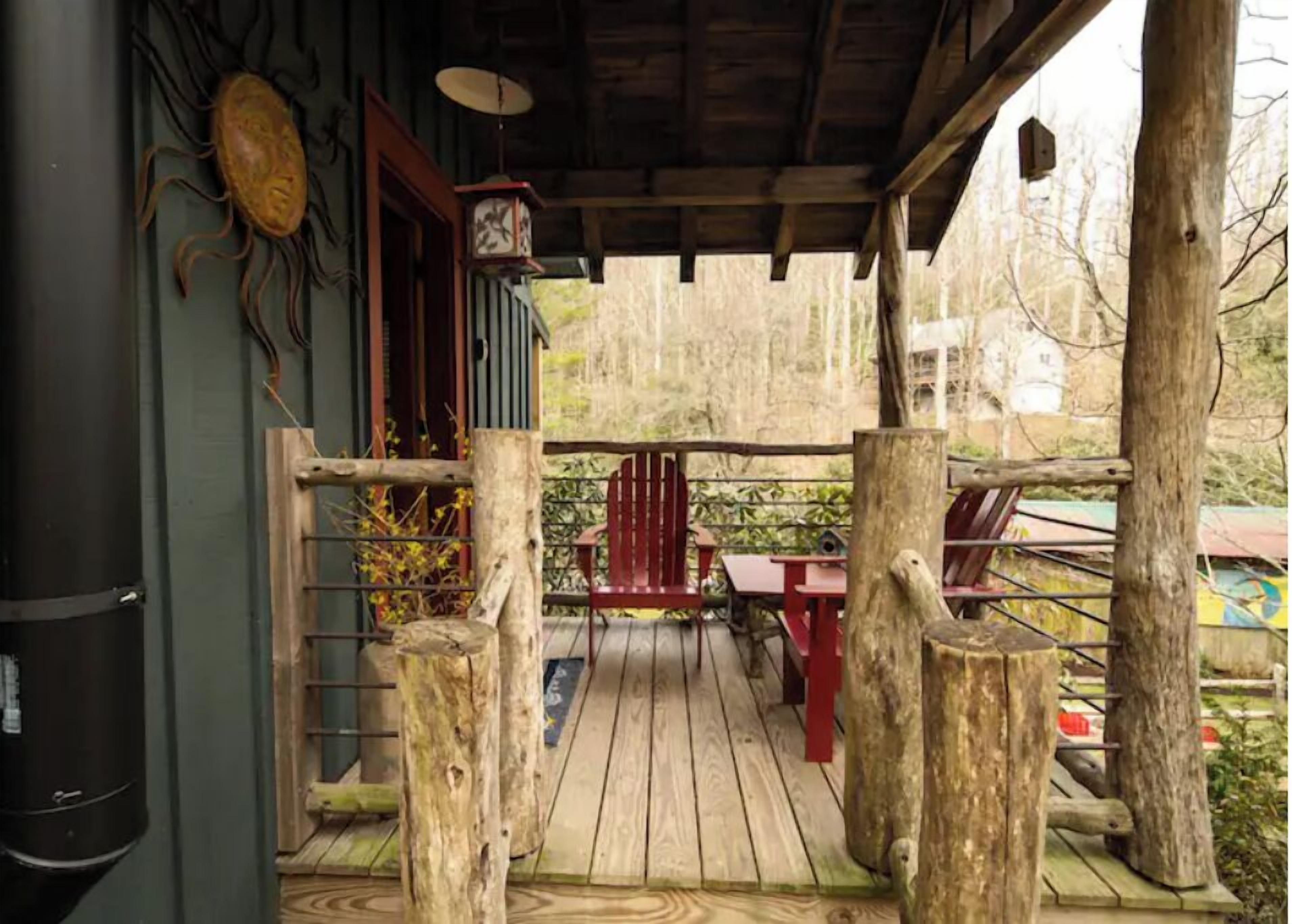 A wooden deck with a red chair and a table, a wooden fence, and a birdhouse.