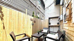 Un petit espace patio avec deux chaises en osier, une table et un tapis à motifs.