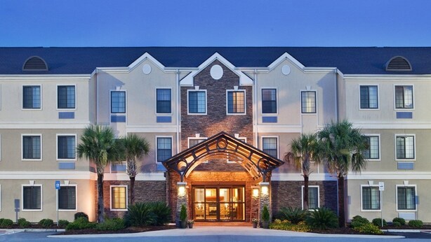 A multi-story hotel with a central entrance featuring a stone facade and a wooden archway.