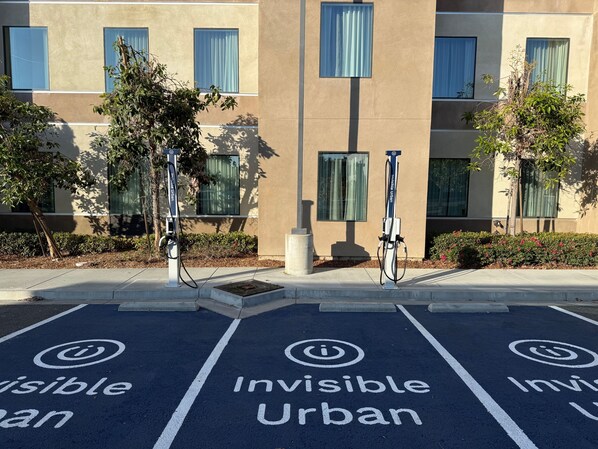 A parking area with electric vehicle charging stations and 'Invisible Urban' painted on the ground.