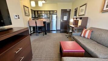 A compact living space with a sofa, a television, a kitchenette, and a dining area.
