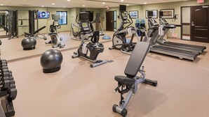 A gym with treadmills, elliptical machines, and exercise balls.