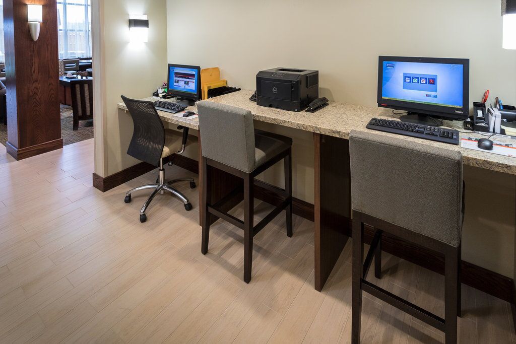 Een hotel werkplek met twee bureaus, elk met een computer, printer en toetsenbord.