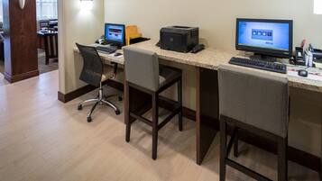 Een hotel werkplek met twee bureaus, elk met een computer, printer en toetsenbord.