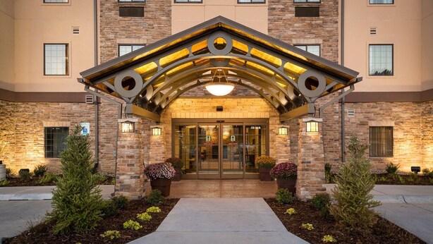 A hotel entrance with a stone facade, a covered entrance area, and potted plants.
