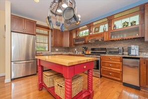 A kitchen with wooden cabinets, a stainless steel refrigerator, a microwave, and a built-in oven. - Sunset Cove by Taylor Made Deep Creek (Swanton)