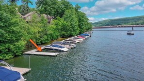 A marina with boats docked along a riverbank, surrounded by lush greenery and a bridge in the background. - 180 Degrees by Taylor Made Deep Creek (Oakland)