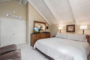 A bedroom with a large bed, a dresser with a mirror, a television, and a sign on the wall. - 180 Degrees by Taylor Made Deep Creek (Oakland)